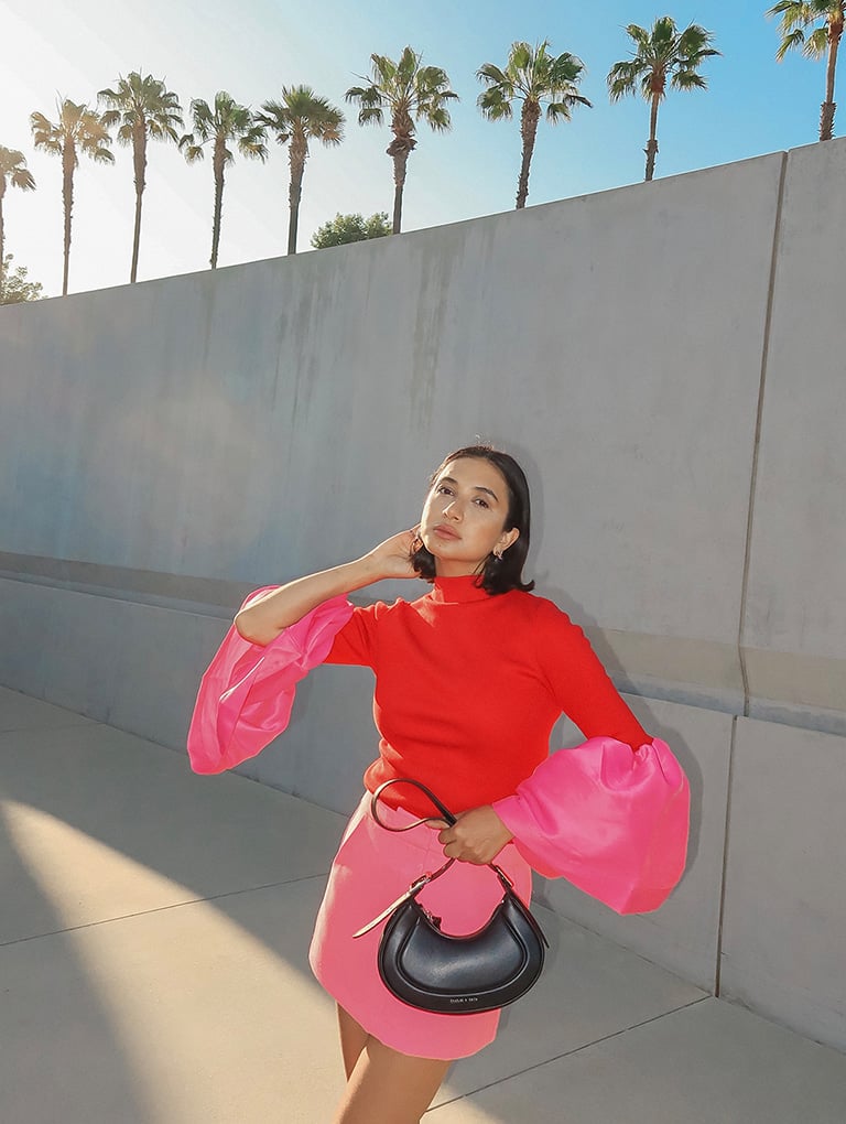 Women’s Petra curved shoulder bag in black and Loey ankle-strap platform pumps in pink, as seen on Navdeep Kaur – CHARLES & KEITH