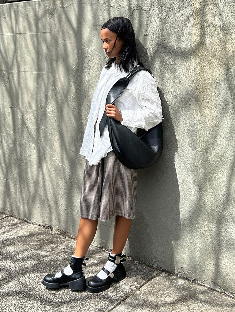 Women’s Toni knotted curved hobo bag in noir & Robbie ankle-strap Mary Jane boots in black, as seen on Vi - CHARLES & KEITH