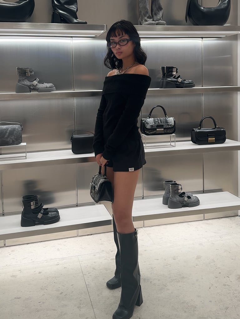 Content creator and model Christine Sosa strikes a pose with the Charlot patchwork denim elongated top handle bag and Robbie platform knee-high boots – CHARLES & KEITH